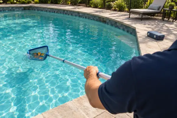 A technician skimming a backyard pool